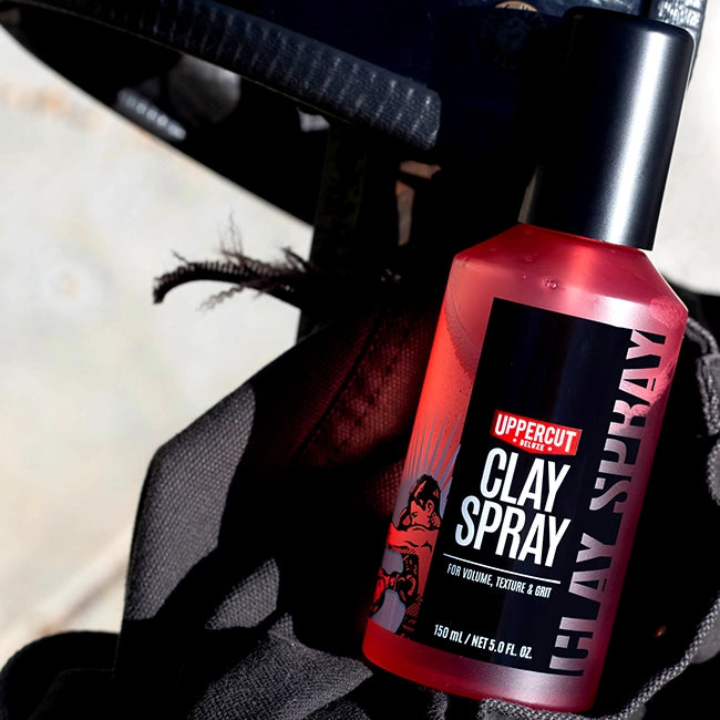 Uppercut Deluxe Clay Spray placed in a heavy canvas bag on a blurred background