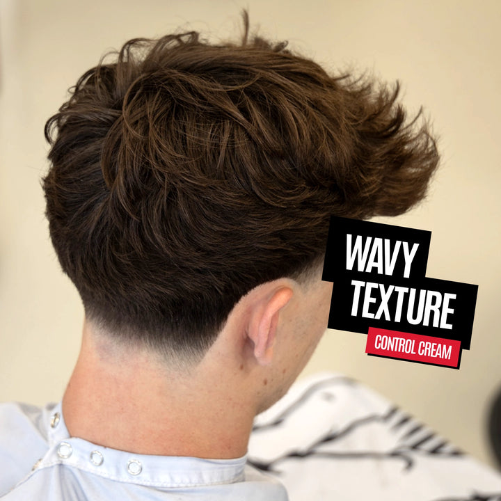 A man shown from the back with styled wavy brown hair, wearing a barber cape. A text overlay on the right reads 'WAVY TEXTURE CONTROL CREAM'.