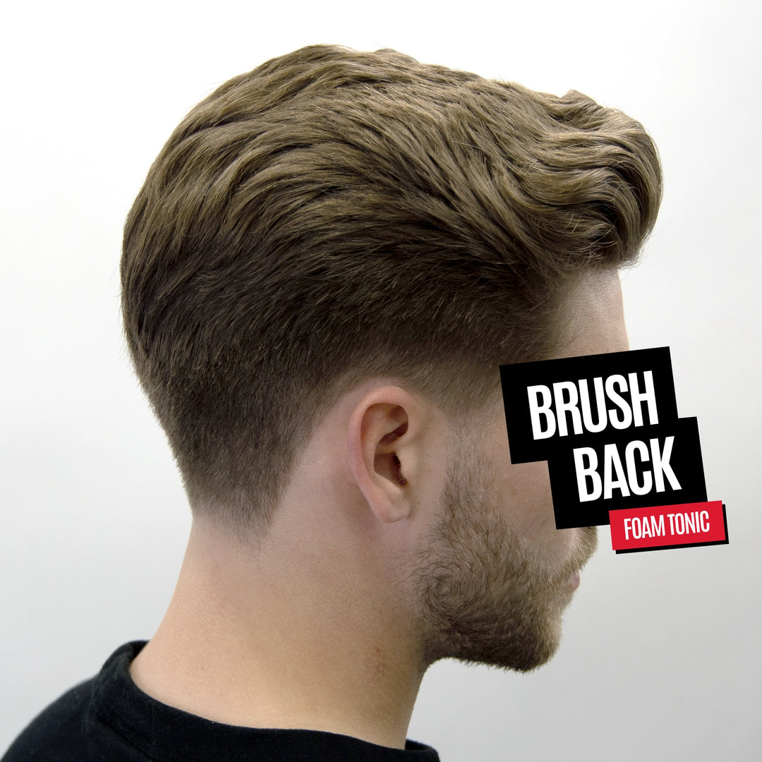 Side profile of a man with styled, voluminous brown hair showing the product in use. A black and red graphic overlay reads 'BRUSH BACK FOAM TONIC'.